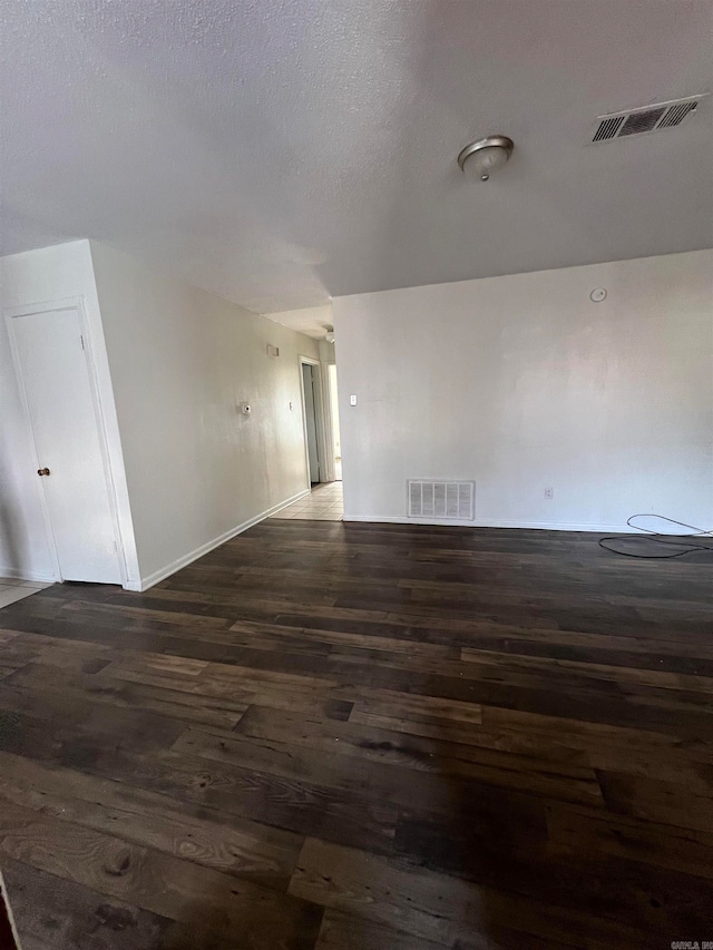 unfurnished room with dark hardwood / wood-style floors and a textured ceiling