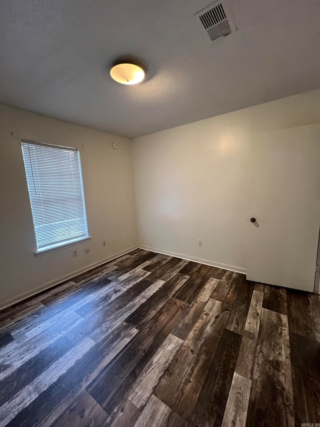 unfurnished room featuring a textured ceiling and dark hardwood / wood-style flooring