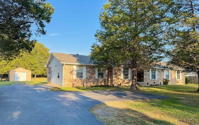 view of front of house featuring a garage, a front lawn, and an outbuilding