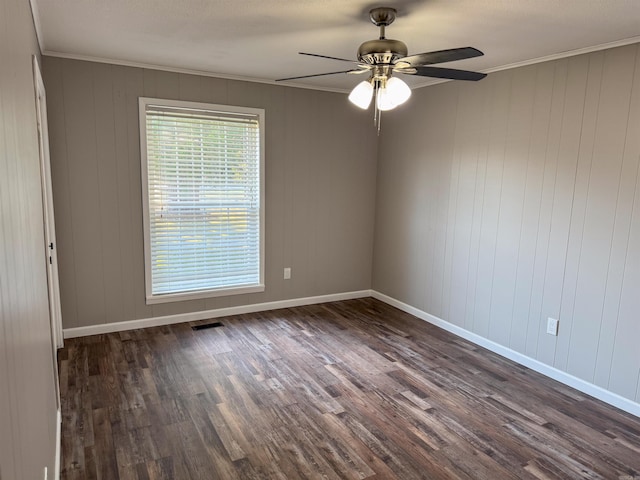 empty room with ornamental molding, wooden walls, ceiling fan, and dark hardwood / wood-style flooring