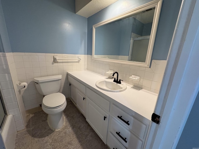 bathroom with toilet, tile patterned flooring, vanity, and tile walls