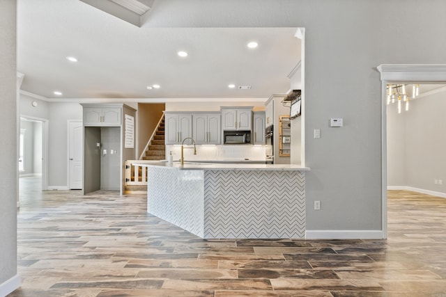 kitchen featuring light hardwood / wood-style flooring, crown molding, tasteful backsplash, and gray cabinetry