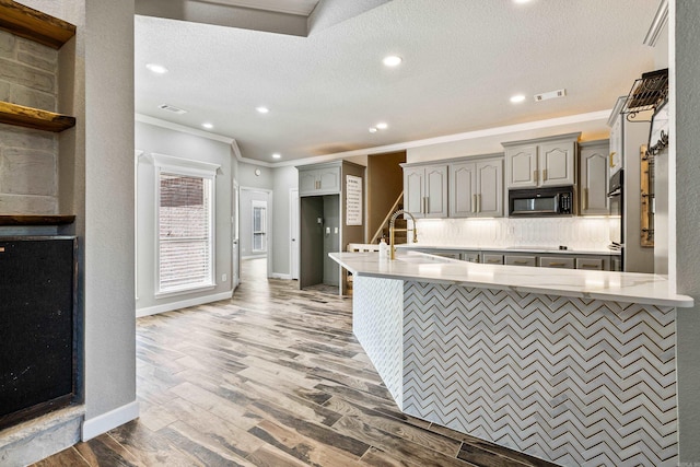 kitchen with sink, hardwood / wood-style floors, kitchen peninsula, and gray cabinets