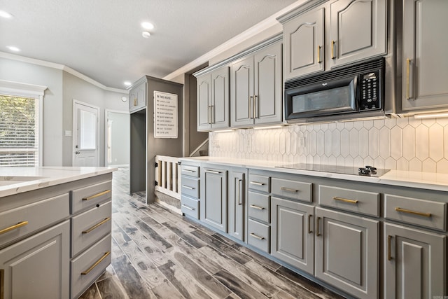 kitchen featuring gray cabinetry, dark wood-type flooring, decorative backsplash, ornamental molding, and black appliances