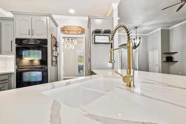 kitchen with ceiling fan, crown molding, black double oven, backsplash, and white cabinetry