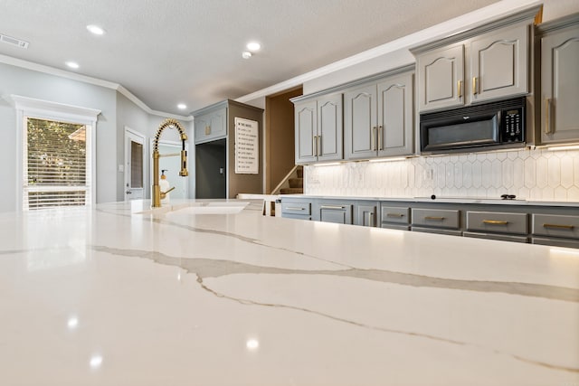 kitchen featuring gray cabinetry, crown molding, stovetop, sink, and decorative backsplash