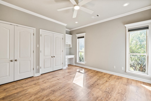 unfurnished bedroom with ceiling fan, multiple windows, two closets, and light hardwood / wood-style flooring