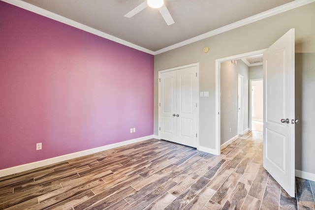 unfurnished bedroom with wood-type flooring, ornamental molding, a closet, and ceiling fan