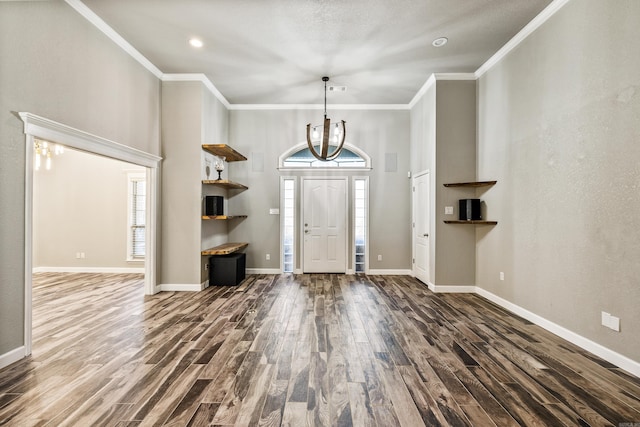 entryway with a notable chandelier, crown molding, and dark hardwood / wood-style flooring