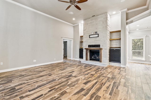 unfurnished living room featuring ceiling fan, crown molding, hardwood / wood-style flooring, and a stone fireplace