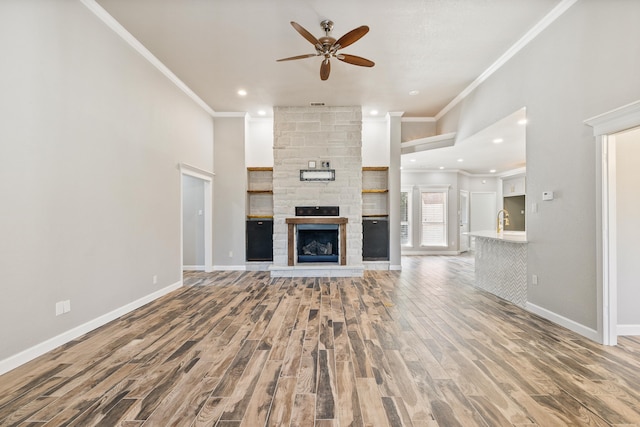 unfurnished living room with ornamental molding, hardwood / wood-style floors, and a stone fireplace