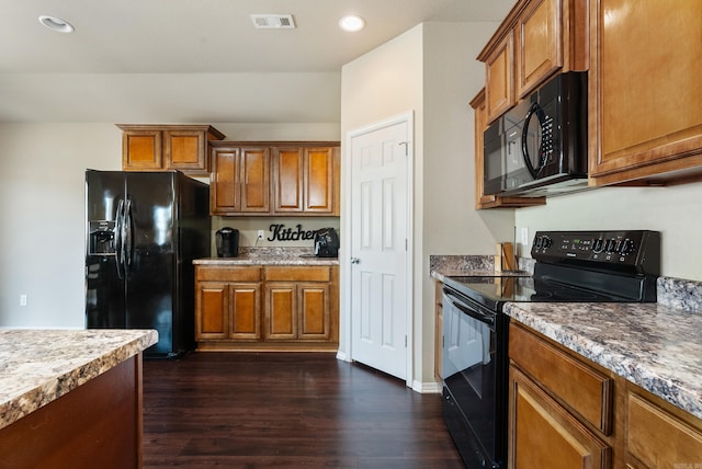 kitchen with light stone counters, dark hardwood / wood-style flooring, and black appliances