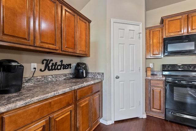 kitchen with dark stone countertops, dark hardwood / wood-style flooring, and black appliances