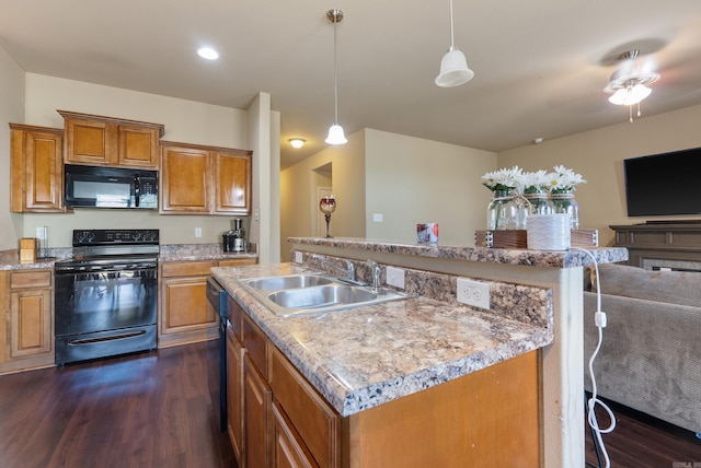 kitchen with black appliances, a center island, sink, dark hardwood / wood-style flooring, and pendant lighting