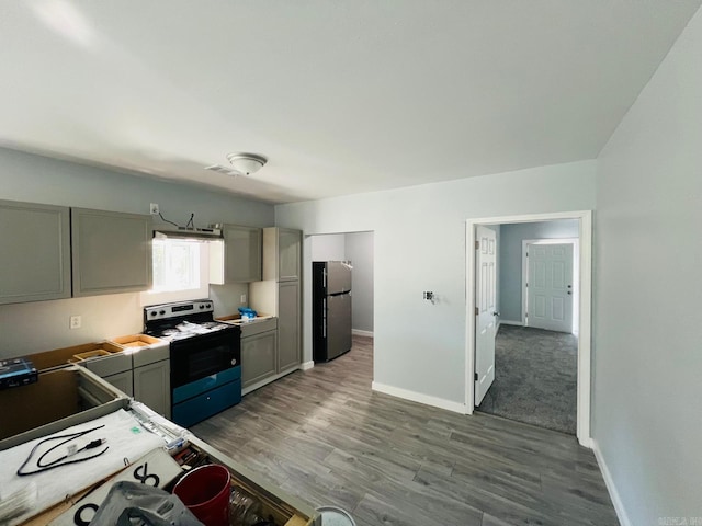 kitchen with gray cabinetry, electric stove, hardwood / wood-style floors, and stainless steel refrigerator