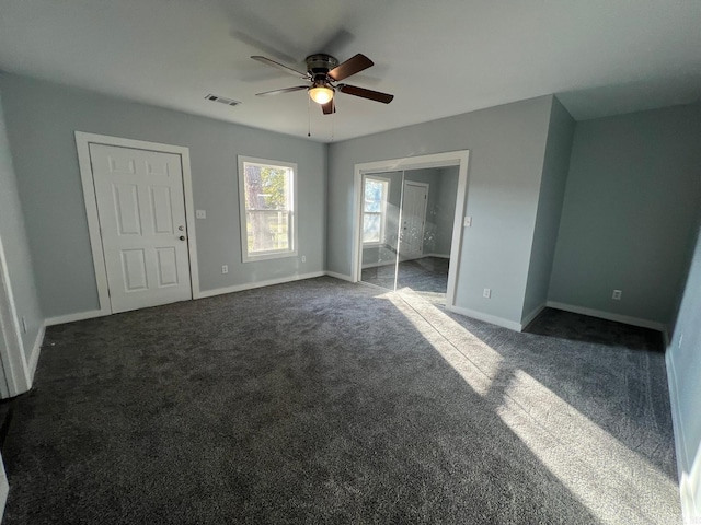 unfurnished bedroom with a ceiling fan, visible vents, dark colored carpet, and baseboards