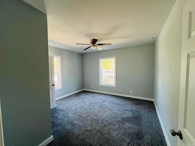 spare room featuring dark colored carpet and ceiling fan