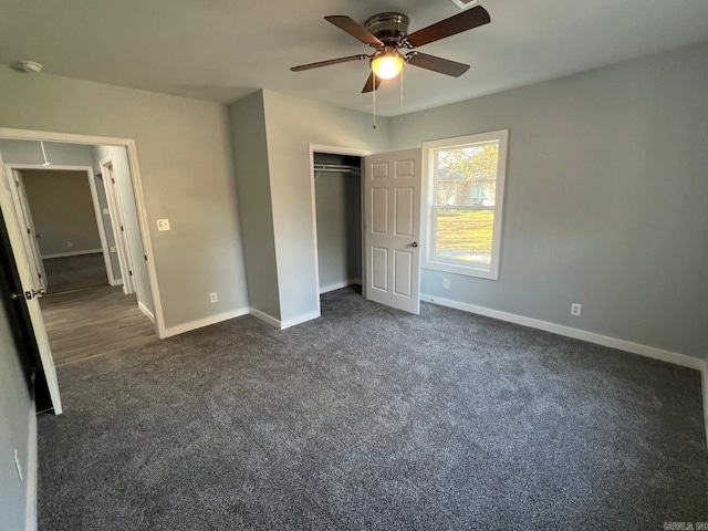 unfurnished bedroom featuring baseboards, dark colored carpet, ceiling fan, and a closet