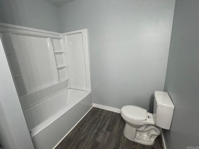 bathroom with toilet, wood finished floors, and baseboards