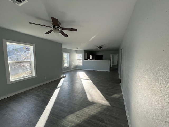 unfurnished living room featuring dark wood-style floors, a ceiling fan, visible vents, and baseboards