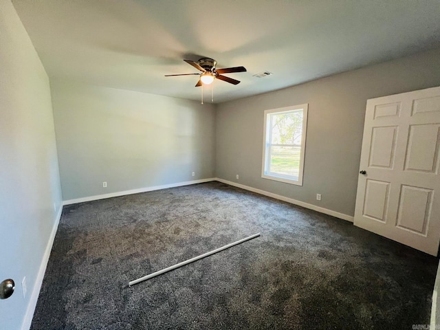 spare room featuring dark colored carpet and ceiling fan