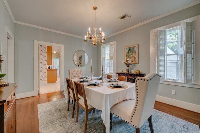 dining room with ornamental molding, a chandelier, and light hardwood / wood-style floors