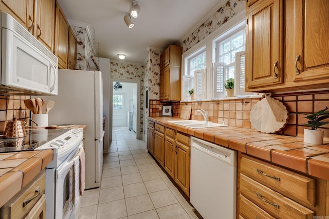 kitchen featuring decorative backsplash, white appliances, sink, tile counters, and light tile patterned floors