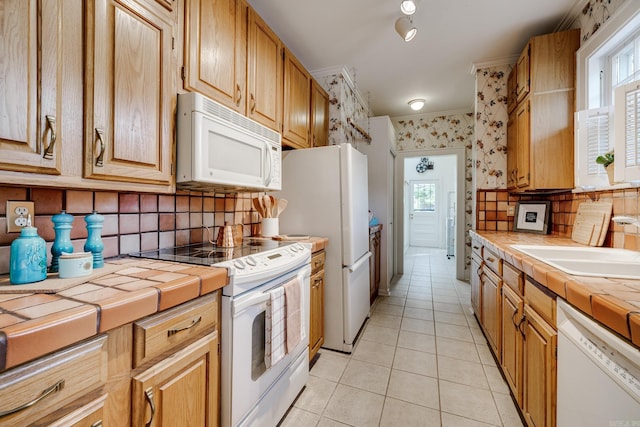 kitchen featuring tile counters, decorative backsplash, white appliances, and light tile patterned floors