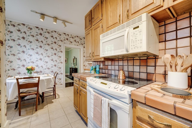 kitchen featuring track lighting, tile counters, white appliances, and light tile patterned floors