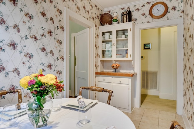 dining area featuring ornamental molding and light tile patterned floors