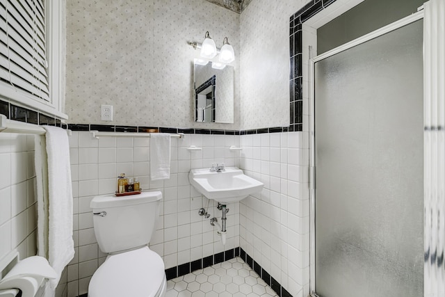 bathroom featuring sink, tile walls, toilet, and a shower with shower door