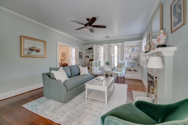 living room featuring ornamental molding, a fireplace, ceiling fan, and wood-type flooring