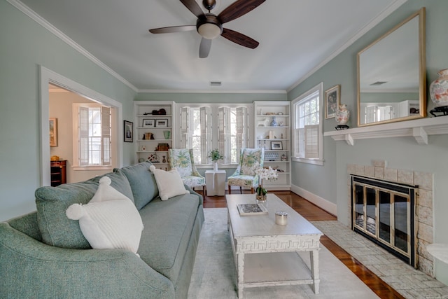 living room with ornamental molding, plenty of natural light, hardwood / wood-style floors, and a tiled fireplace