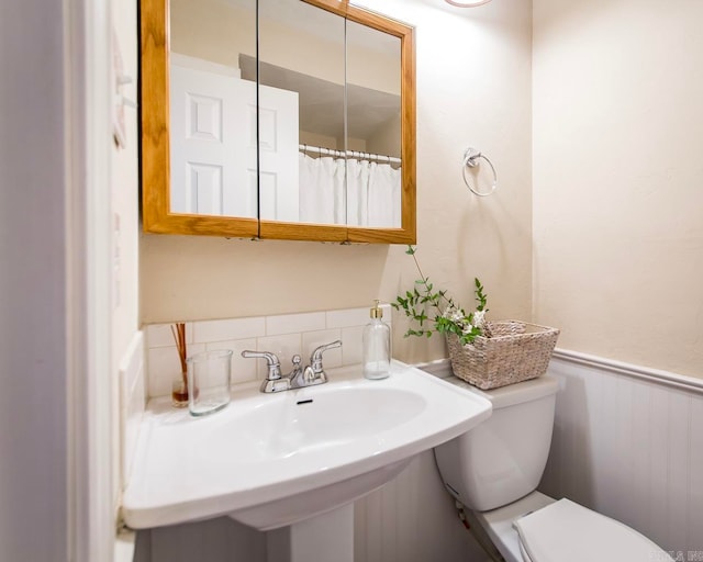 bathroom with walk in shower, sink, and toilet