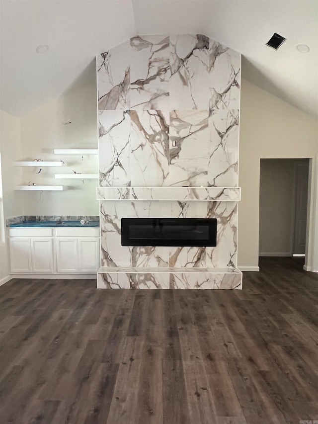 unfurnished living room with vaulted ceiling, dark hardwood / wood-style floors, and a high end fireplace