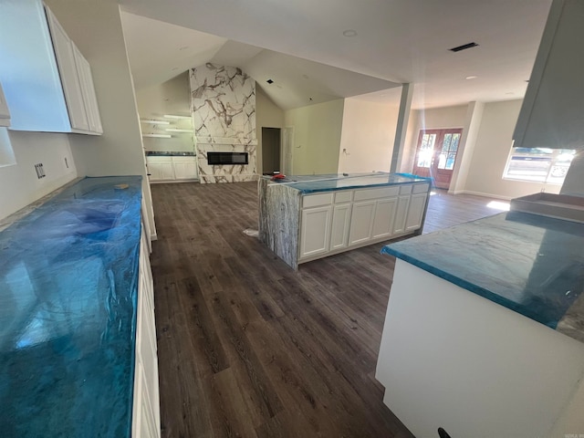 kitchen featuring lofted ceiling, dark wood-type flooring, white cabinets, and a fireplace