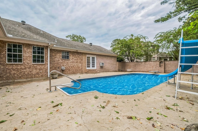 view of swimming pool with a patio area, a water slide, and a diving board