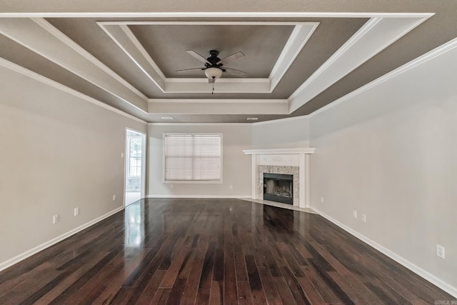 unfurnished living room featuring dark wood-type flooring, ceiling fan, crown molding, and a tray ceiling