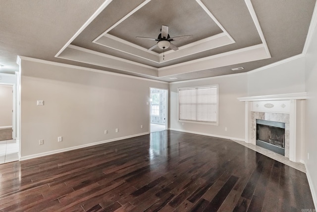 unfurnished living room with ceiling fan, a raised ceiling, dark hardwood / wood-style flooring, and a fireplace