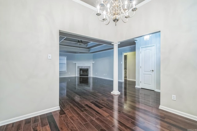 interior space featuring a premium fireplace, ornamental molding, ornate columns, and dark hardwood / wood-style flooring