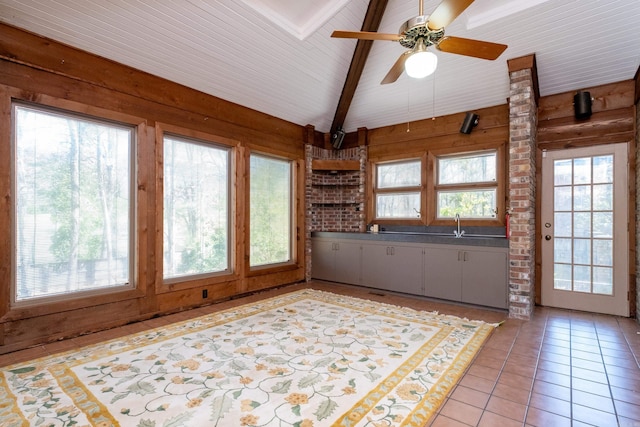 unfurnished sunroom featuring vaulted ceiling with beams, ceiling fan, and a wealth of natural light