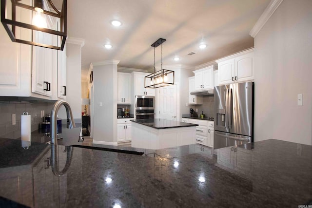 kitchen with a kitchen island, white cabinets, pendant lighting, appliances with stainless steel finishes, and tasteful backsplash