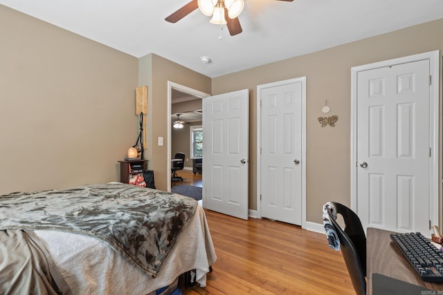 bedroom with ceiling fan, multiple closets, and light wood-type flooring