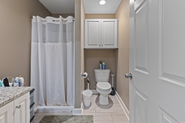 full bath with a shower stall, vanity, baseboards, and toilet