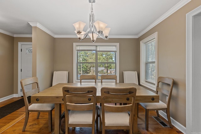 dining room with crown molding, visible vents, an inviting chandelier, and wood finished floors