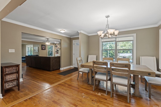dining area featuring crown molding, an inviting chandelier, baseboards, and light wood-type flooring
