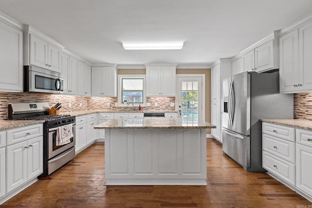 kitchen featuring backsplash, white cabinetry, a center island, stainless steel appliances, and dark wood-style floors
