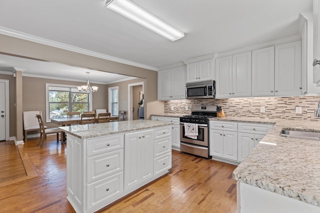 kitchen with a center island, appliances with stainless steel finishes, hanging light fixtures, and white cabinets