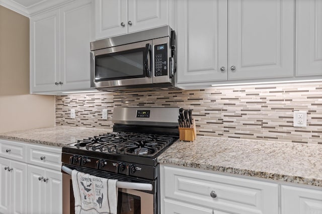 kitchen featuring white cabinetry, backsplash, light stone counters, and appliances with stainless steel finishes