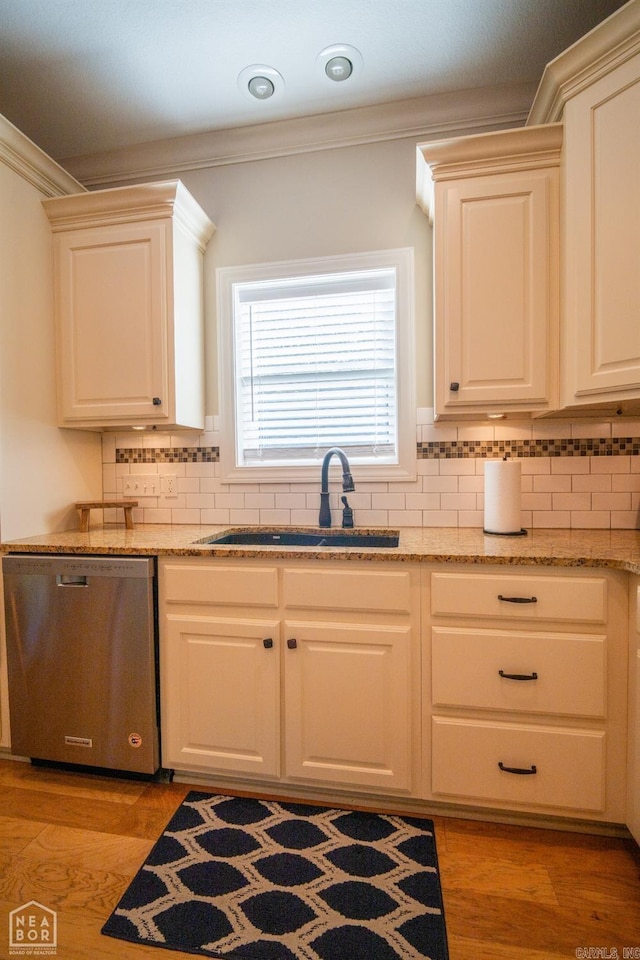 kitchen with sink, backsplash, light hardwood / wood-style floors, stainless steel dishwasher, and crown molding